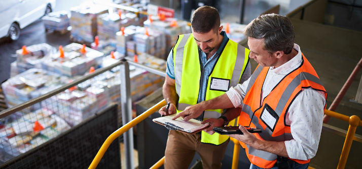 Two men looking at a despatch notice in a warehouse