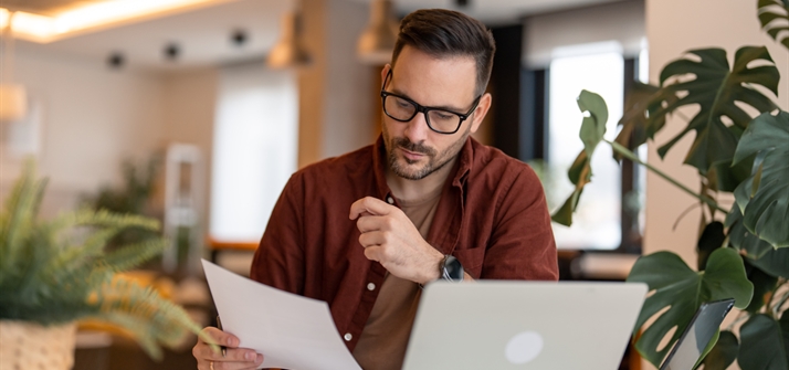 Man reading form next to laptop