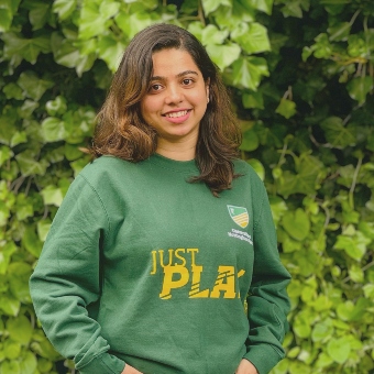 Pooja Mooladka standing infront of a bush on campus