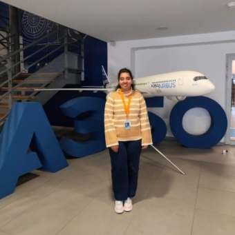 Para Saraiya standing infront of a sign and model of an A350 airplane