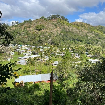 A view of a Fijian village in a valley with mountains behind