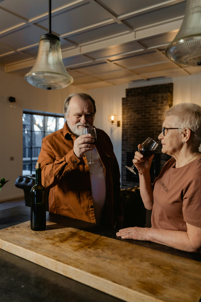 Two older people in pub drinking glasses of wine