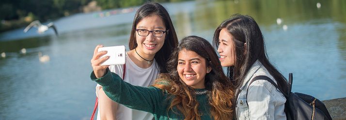 Female students posing for a photo by the lake 714x249