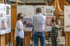A group of three people at the architecture 2021 exhibition looking at student work.