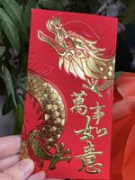 Person holding a red envelope with gold dragon decoration.