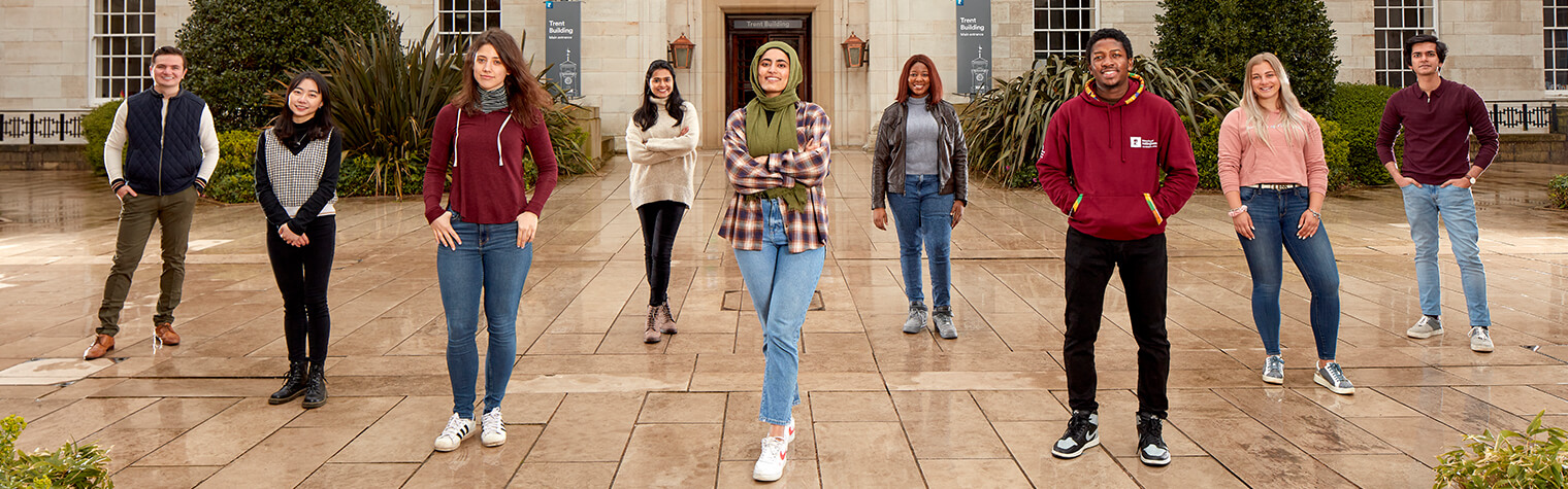 A group of students of stand socially distanced in the courtyard of an old building