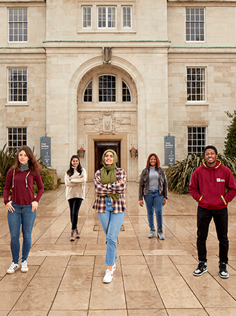 A group of students of stand socially distanced in the courtyard of an old building