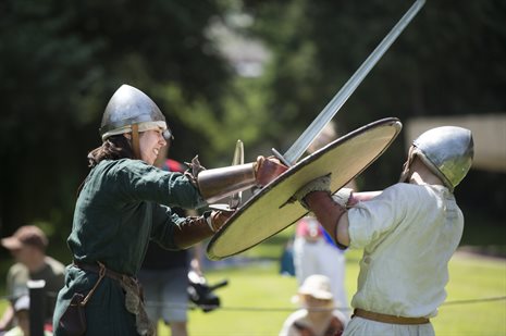 Someone dressed as a Viking striking their sword on a Saxon's shield