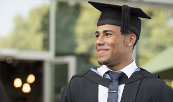 A student in a graduation gown and cap, smiling