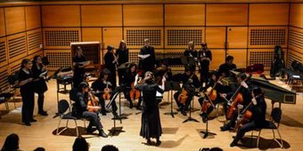 A conductor leads an orchestra in the recital hall.