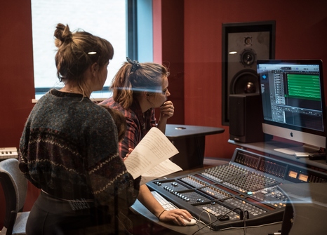 Two students look at a computer in the recording studio