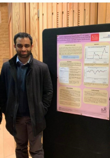 Photo of Hari Pai standing next to a poster displaying his research