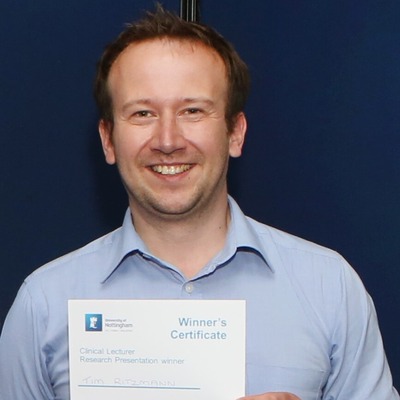 Portrait of Tim Ritzmann smiling and holding a certificate