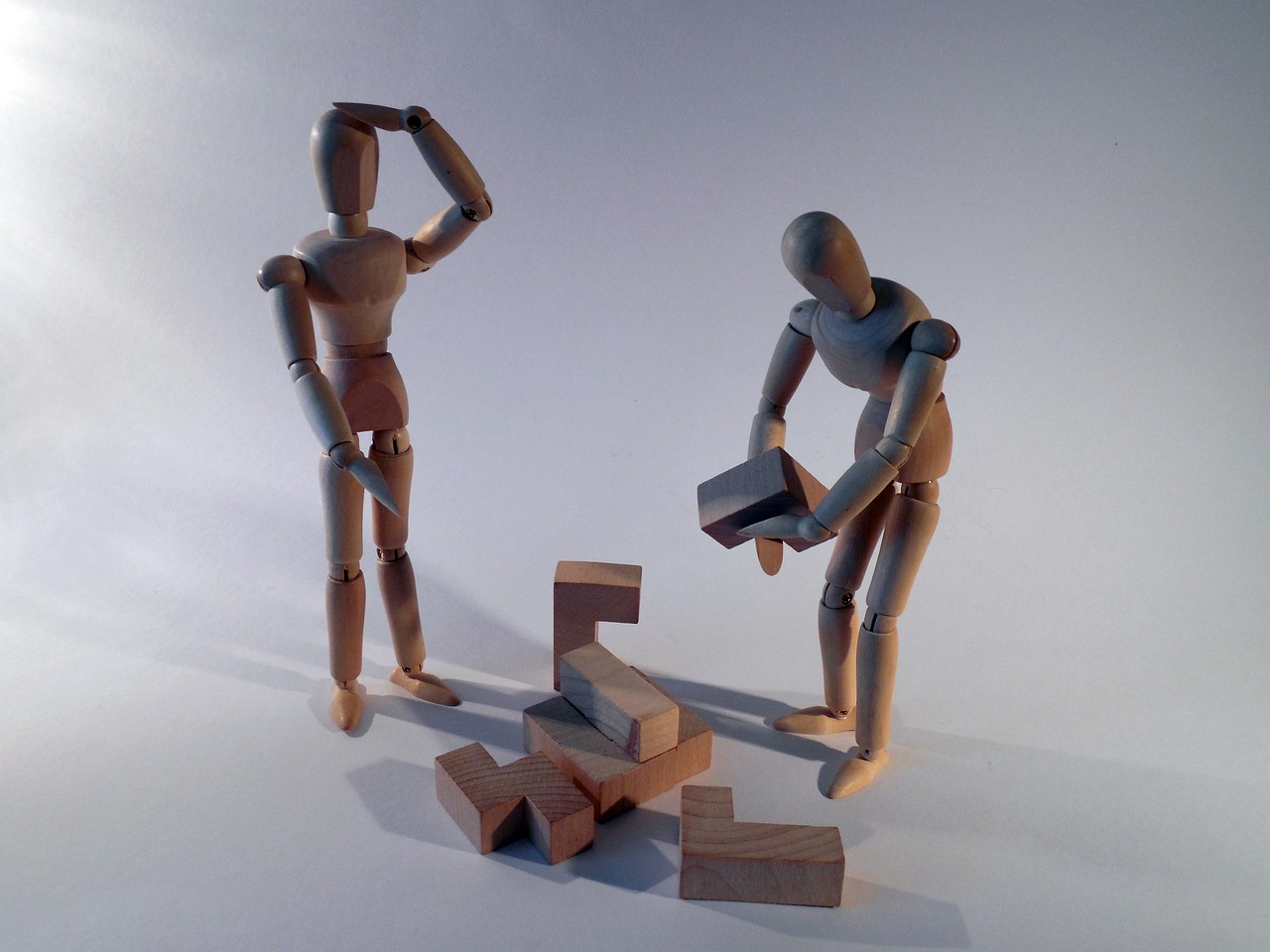 Two wooden figures attempt to build a tower