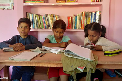 A group of children reading books in Dr Kumar's village library in Kalyanpur, northern India