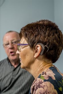 A person wearing a cochlear implant talking with an out of focus person