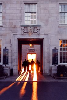 A group of students walk through the Trent Building courtyard at sunset