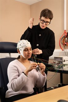 A researcher with a participant wearing an electrode cap