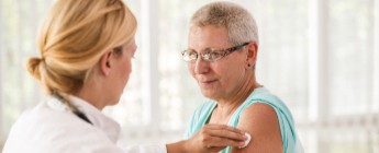 A female doctor injecting an elderly female patient