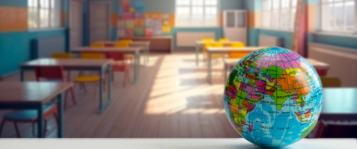 Globe in the foreground with empty school classroom as background