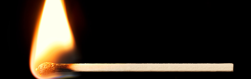 A lit match with flame against a black background