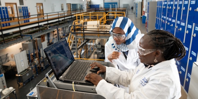 Two researchers working on laptop in engineering lab