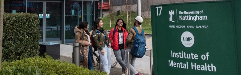 Mixed group of students smiling and walking past "Institute of Mental Health" sign