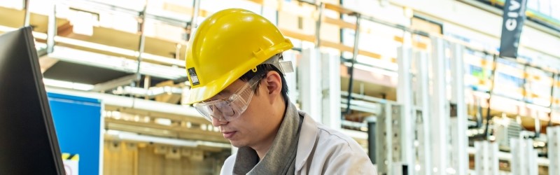 Researcher in yellow safety helmet in load testing lab