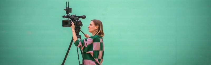 Woman using broadcast camera against green screen background