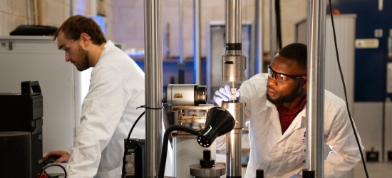 Student and technician wearing white coats in load testing lab