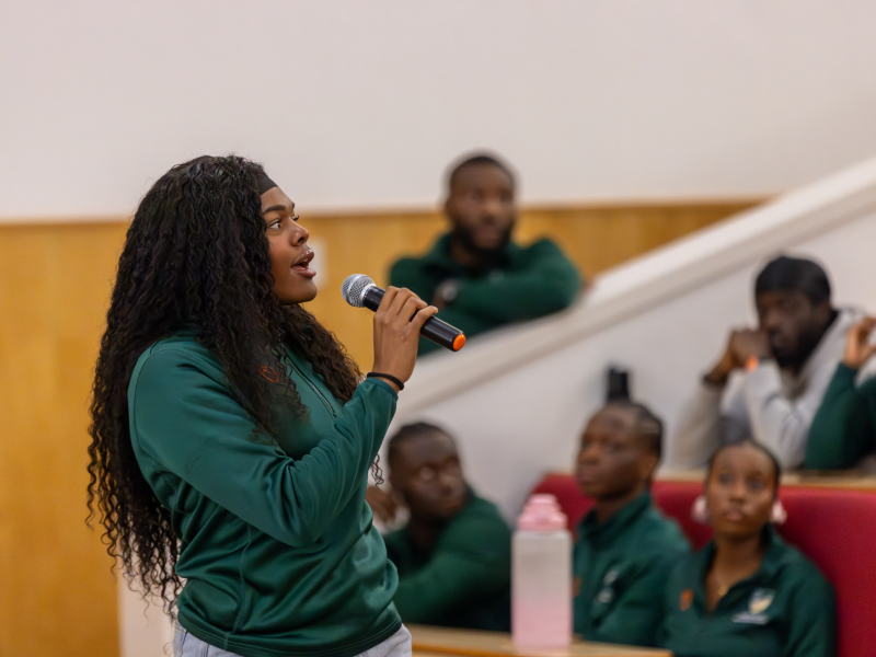 Female student speaks with microphone at Black Sport Collective launch