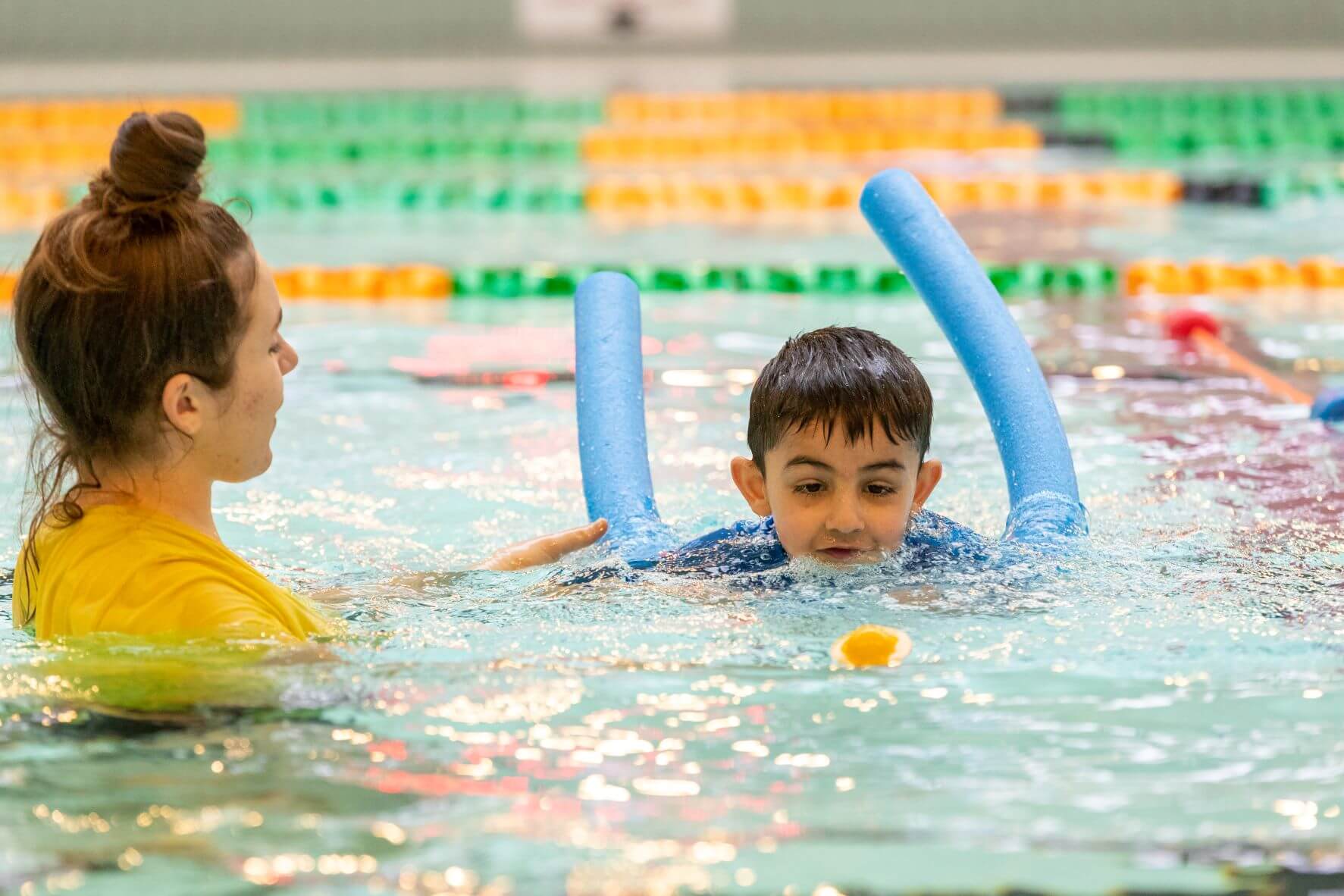 Young boy learning to swim with instructor