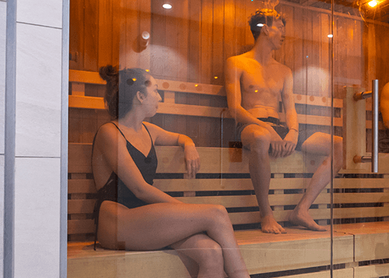 A female student and a male student relaxing in the sauna in our Health and Wellbeing Suite at David Ross Sports Village