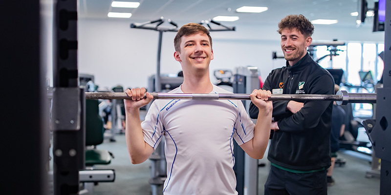 A student working out in our fitness suite at Jubilee Sport Centre with the support of one of our fitness instructors