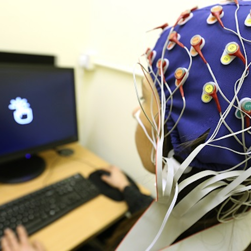 Student wearing cap to measure brain activity while reading screen content