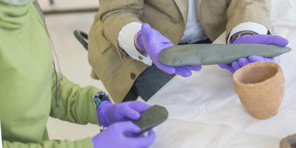 Archaeologists discuss and examine ancient artifacts in a museum setting.