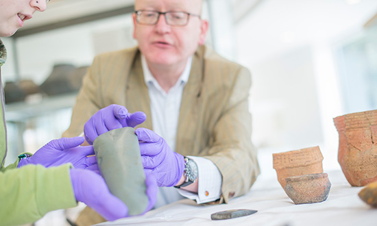 An academic and a student handling artefacts in the University Museum