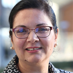 Professor Meryem Duygun. Meryem is wearing glasses, has dark hair which is tied back and is wearing a black and white collared jacket.