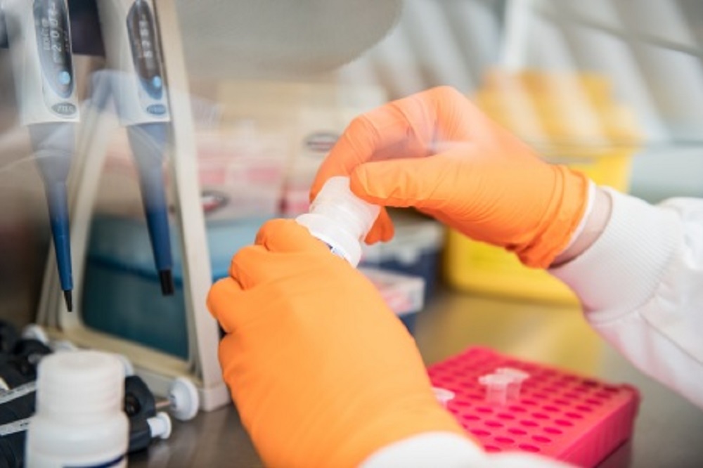 Person wearing orange gloves in a laboratory carrying out a test