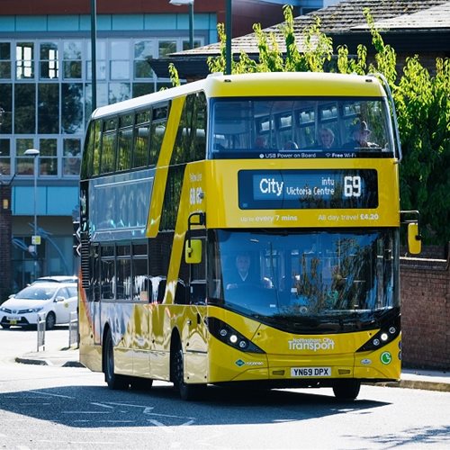 Nottingham City Transport double decker yellow bus going down a street.