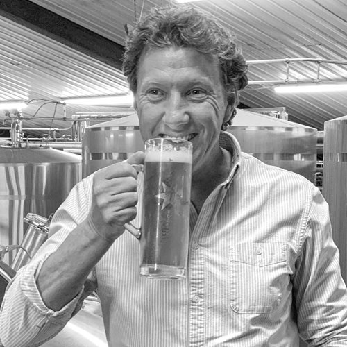Photo of Matthew Wilson, Managing Director of Freedom Brewery, stood in the brewery with a pint glass in his hand.