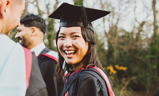 Student at graduation with friends smiling at the camera