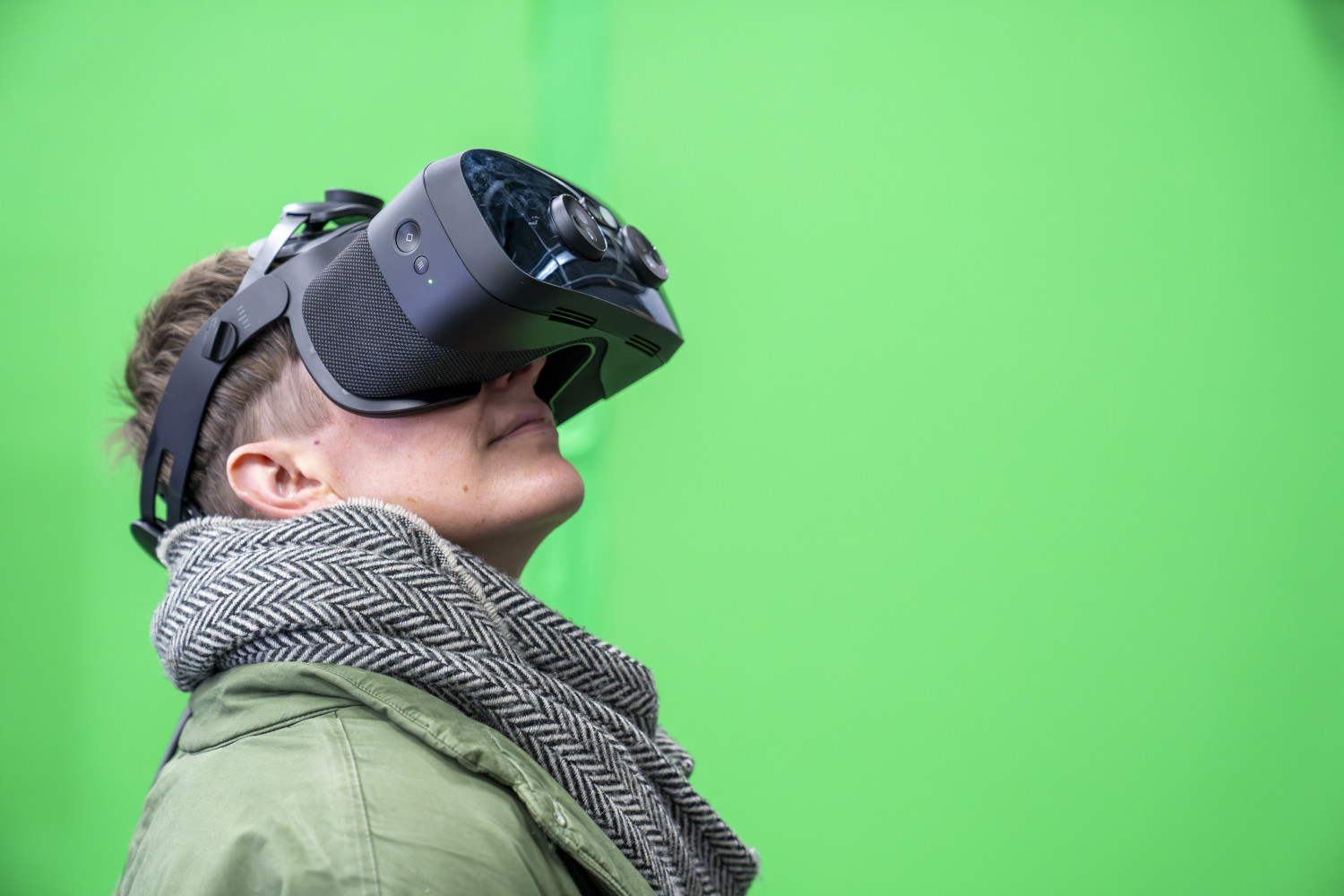 A woman wearing a vr headset. She is in front of a green screen