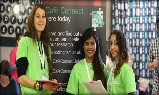 Three smiling researchers standing in front of Cafe Connect banner