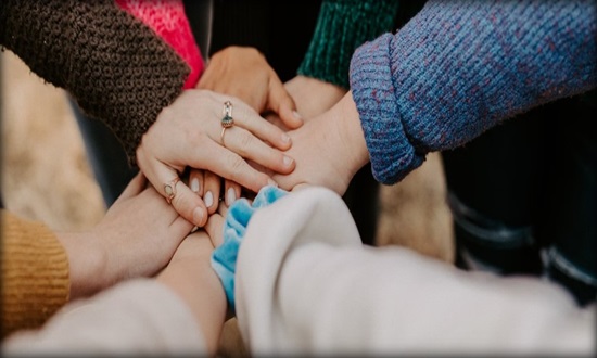 Close up of group of hands on top of each other in a circle