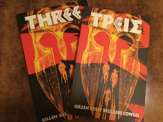 Two copies of the graphic novel 'Three' displaying a Spartan warrior's helmet on the covers