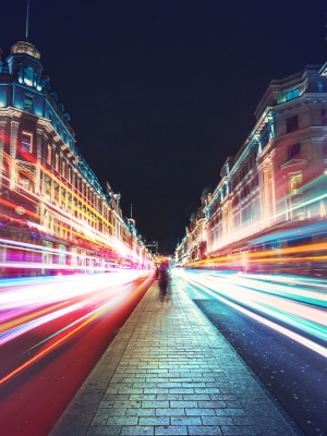 A nighttime cityscape with long exposure light trails from moving vehicles, capturing the bustling energy of the urban environment.