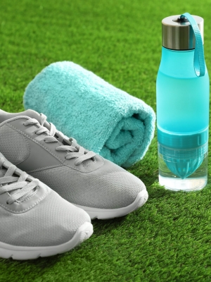 A pair of running trainers and a water bottle on grass