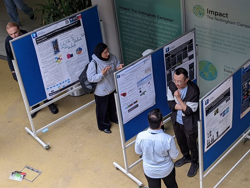 Staff and students reading research posters displayed in the ESLC building