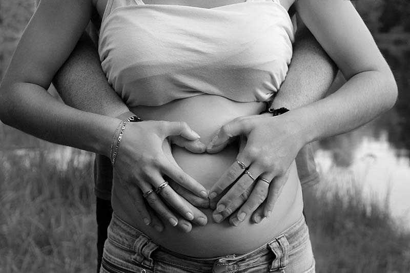 Pregnant woman with man holding hands over tummy